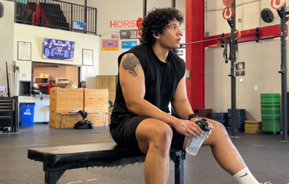 Coach Fernando resting on a bench between sets