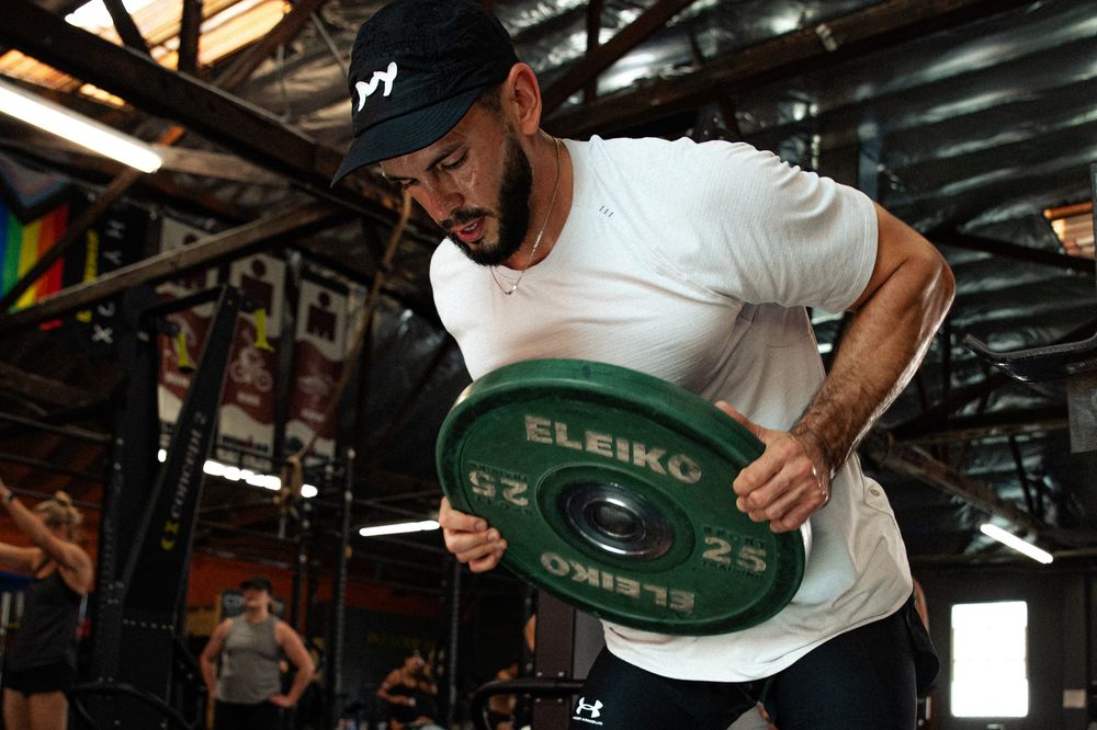 An athlete carrying a 25 kg plate in GSTRENGTH