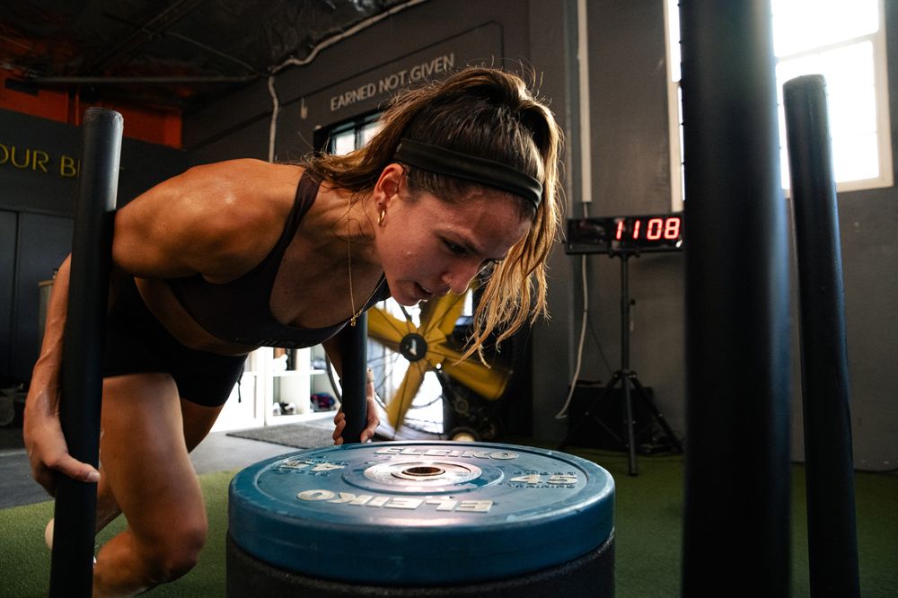 An athlete driving a loaded sled during HYROX training at Ganbatte Fitness